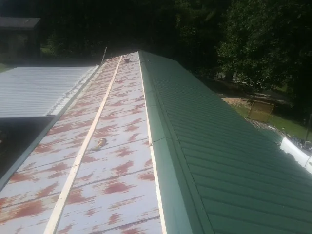 Old rusted panels beside newly installed green metal roofing — Wind Damage Roof Repair by Roofing Brothers in Warrington