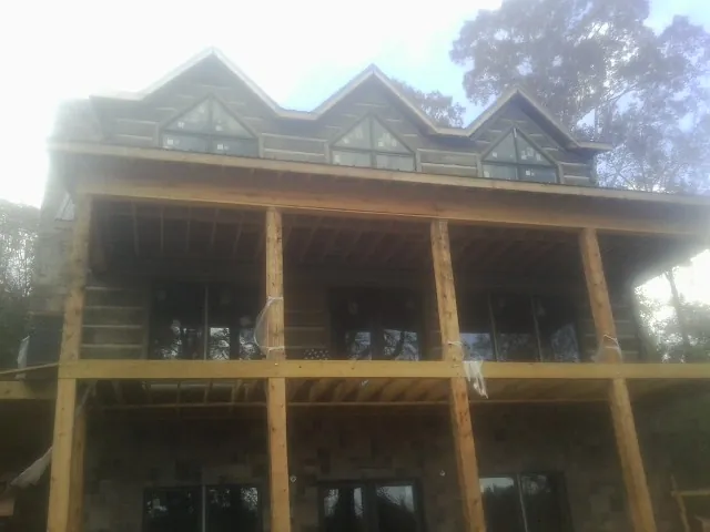 Dormers and porch framing on a large log home under construction — Roof Coating work by our crew in Warrington