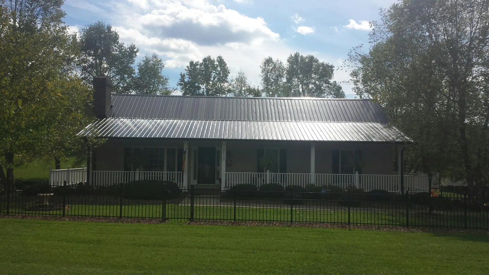 Gray metal roof on a brick ranch with a full width front porch — Gutter Guard Installation work by our crew in Warrington