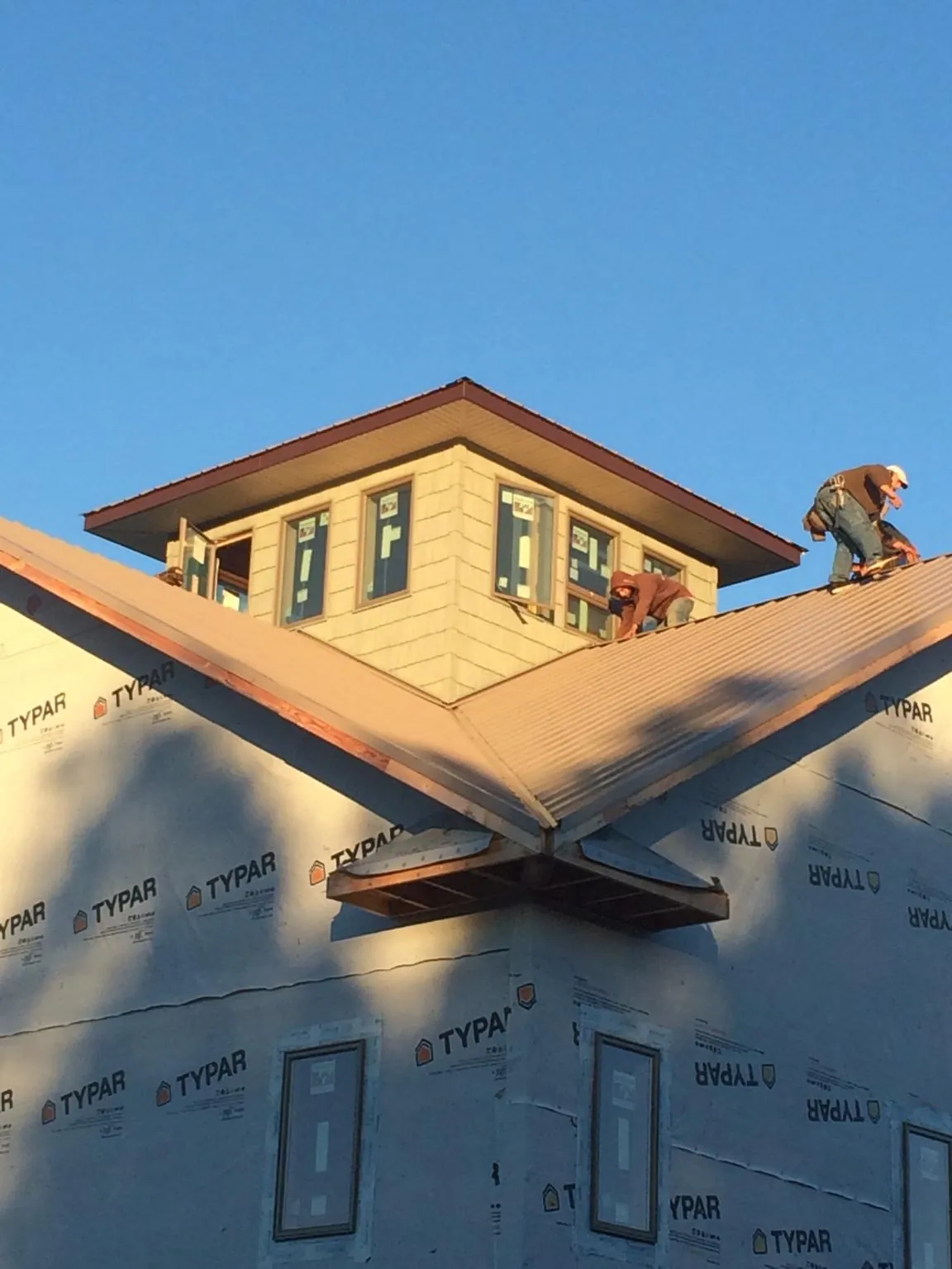 Roofers working around a rooftop cupola on a new metal roof at sunset — Roof Waterproofing in Warrington by Roofing Brothers